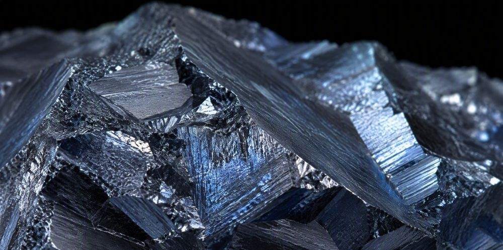 Extreme close-up of a silicon lump fracture surface showing faceted crystals with a bluish sheen.