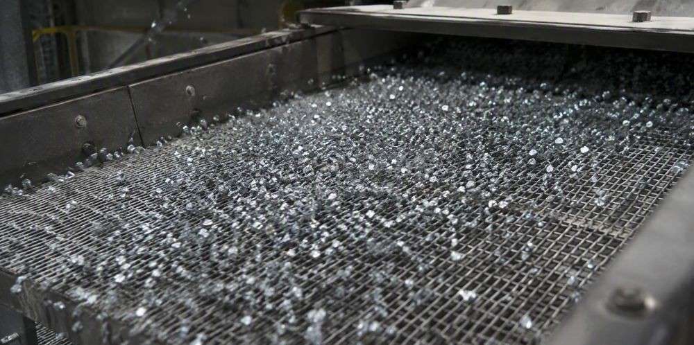 Silicon granules bouncing across the mesh of an industrial vibrating screen.