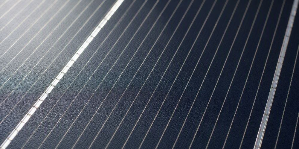 Close-up of a dark monocrystalline solar cell surface with fine silver gridlines.