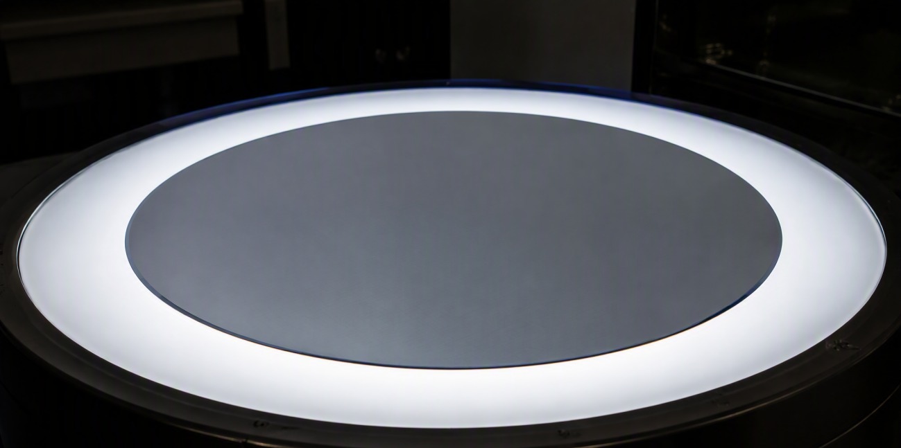 A monocrystalline silicon wafer glowing on an illuminated round inspection table.