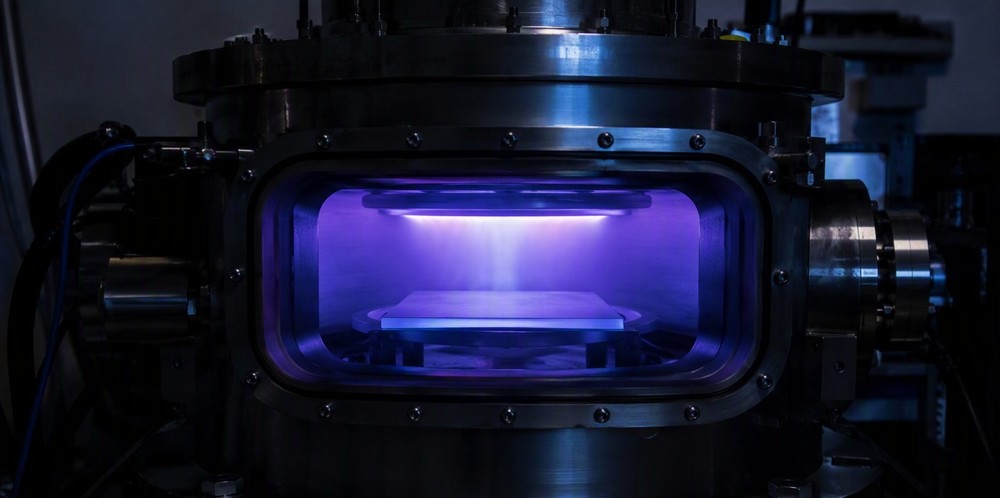Violet plasma glowing inside a deposition chamber coating a glass substrate with thin-film silicon.