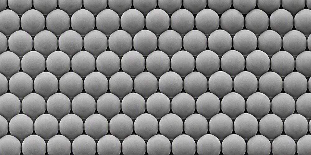 A grayscale microscopic view of uniform silica microspheres packed shoulder to shoulder.