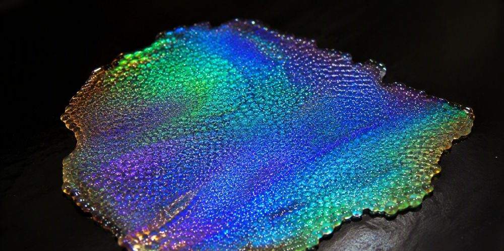 An iridescent film of self-assembled silica spheres shimmering with structural color.