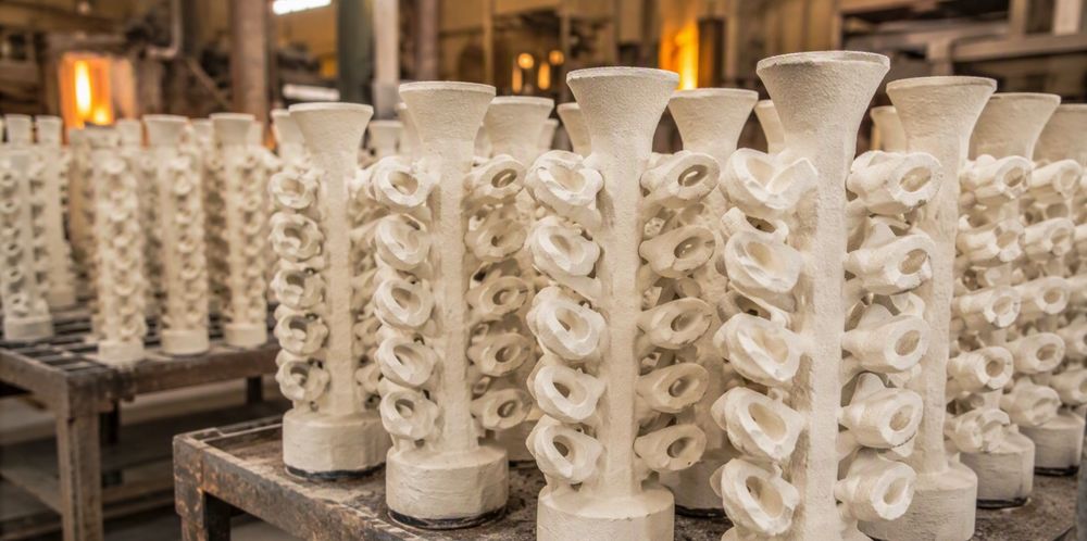 Rows of white ceramic investment-casting shell molds on foundry racks.