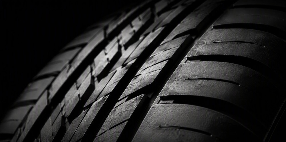 A close view of a plain black tire's deep tread pattern.