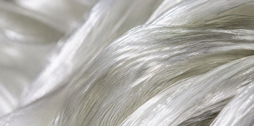 Silky translucent glass fiber strands bundled in soft light.