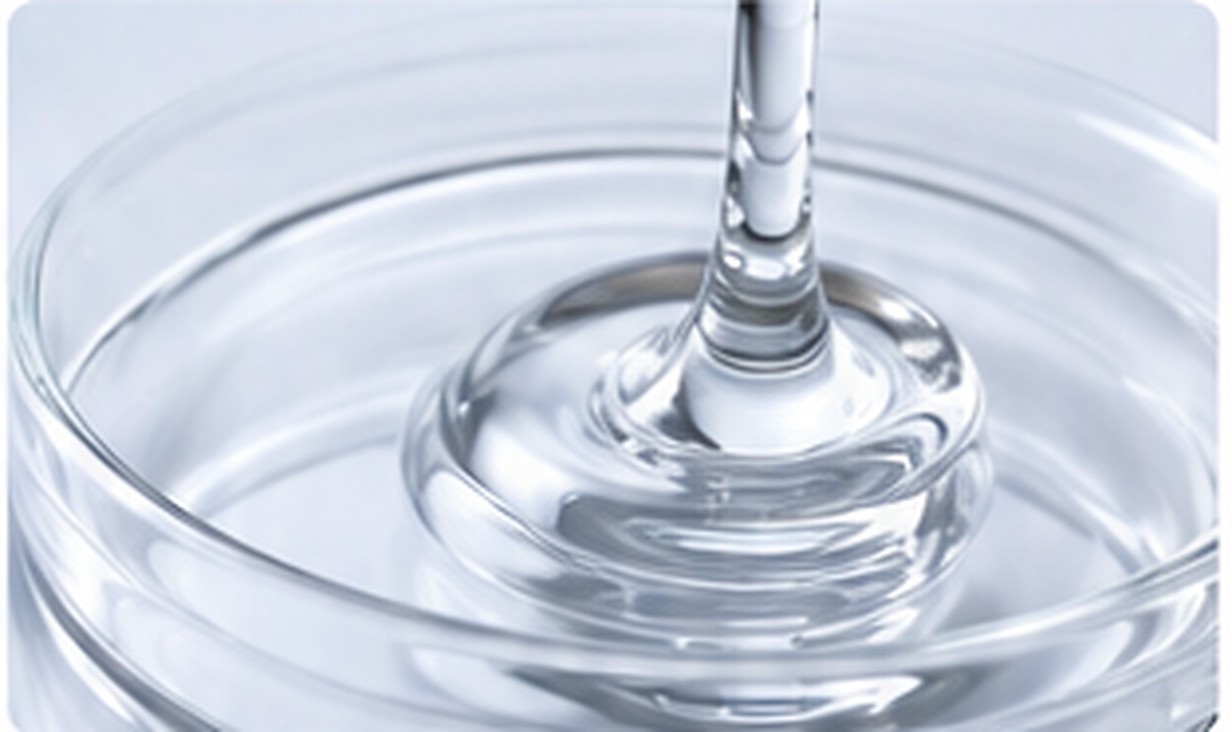 Glossy transparent silicone liquid swirls inside a clean glass dish with strong optical clarity.