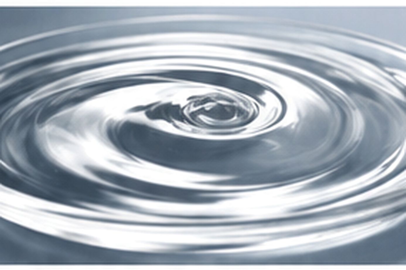 A glossy circular swirl forms in a transparent fluid surface viewed from above.