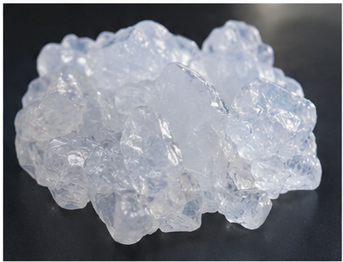 Translucent silicone gum sample shown as a compact high-molecular-weight polymer mass on a dark surface.