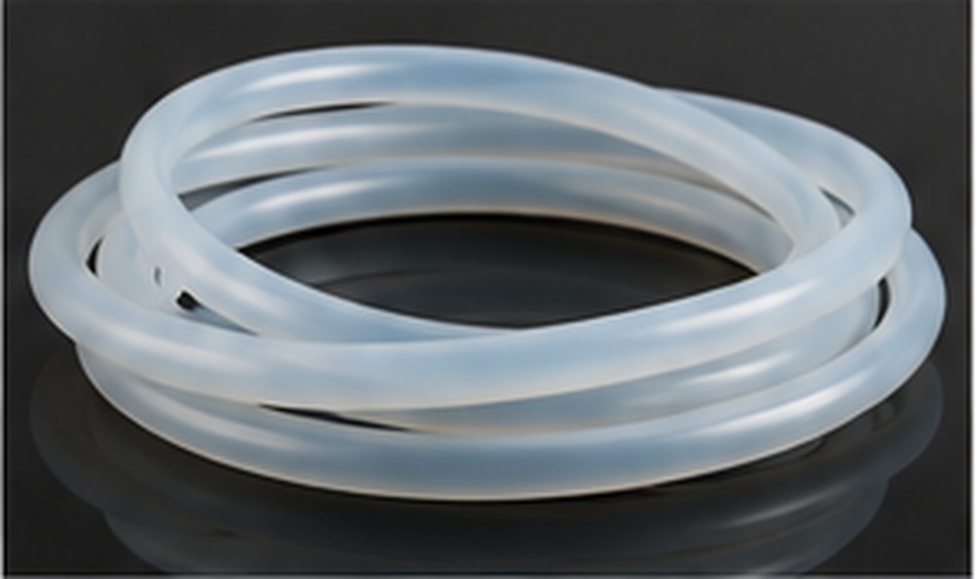 Coiled translucent silicone rubber tubing arranged on a dark reflective work surface.
