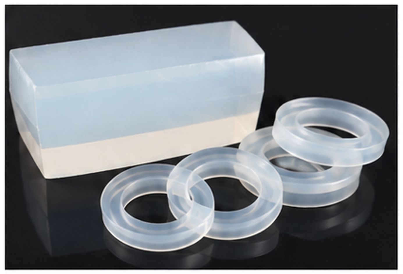 Translucent silicone rubber block with clear molded rings arranged on a dark reflective surface.