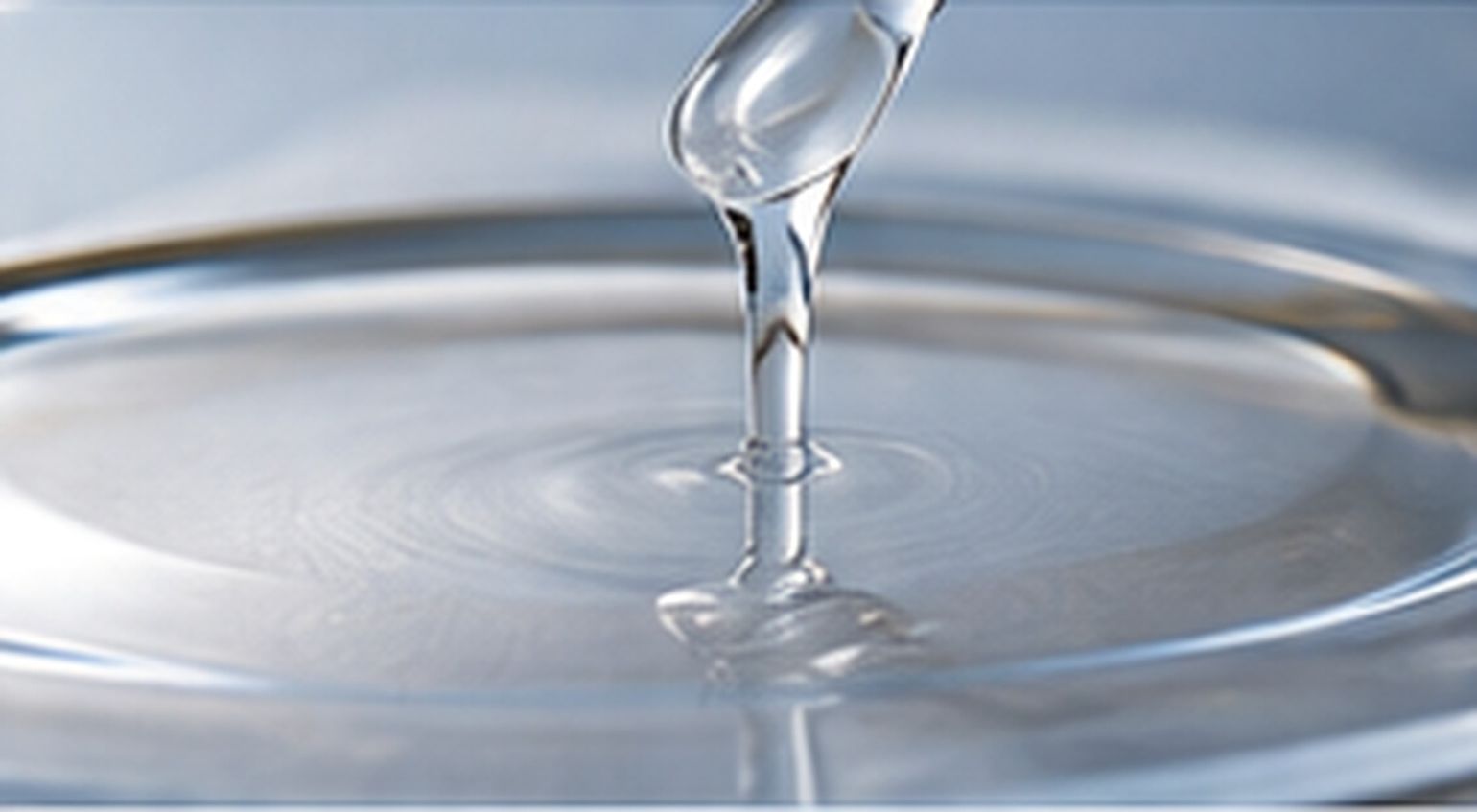 Clear viscous silicone resin solution flowing onto a smooth metallic coating surface.