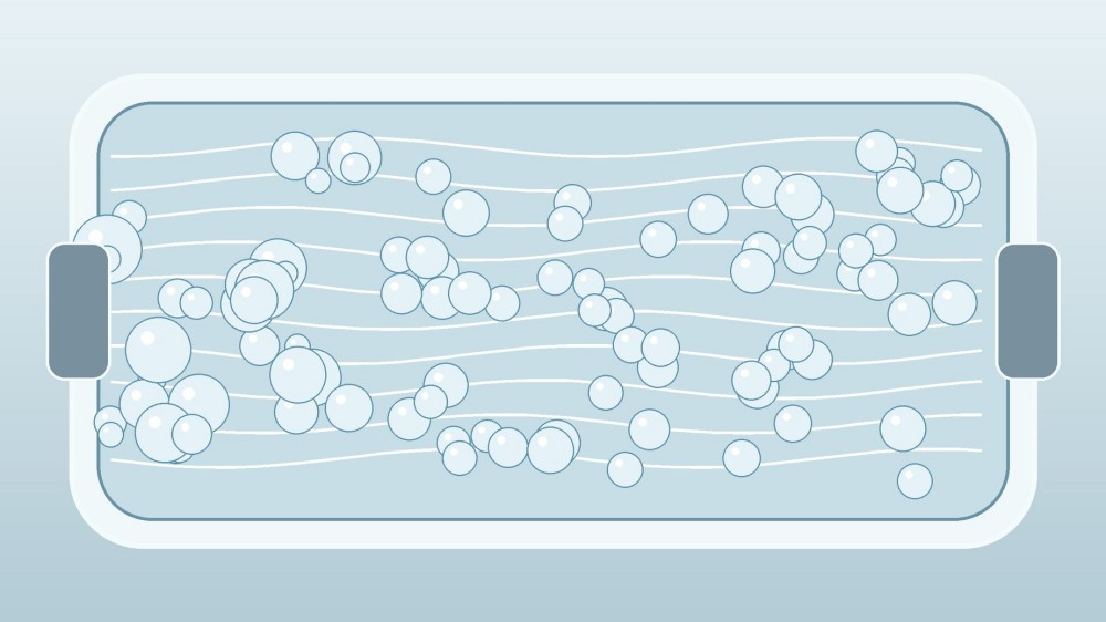 A transparent flow cell contains evenly distributed round droplets moving along parallel streamlines.
