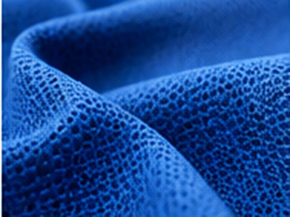 Macro view of vivid blue knitted technical fabric with a fine open-loop structure.