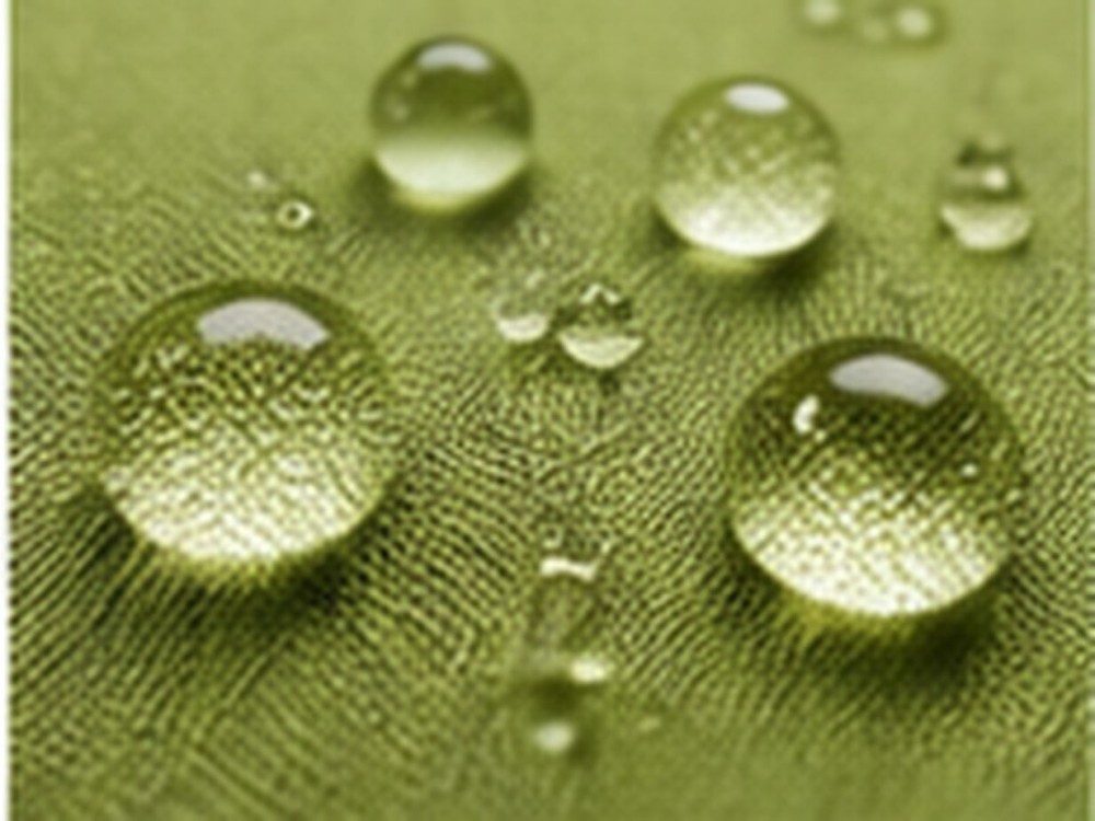 Water droplets resting on a green woven fabric surface used to illustrate controlled wetting behavior.